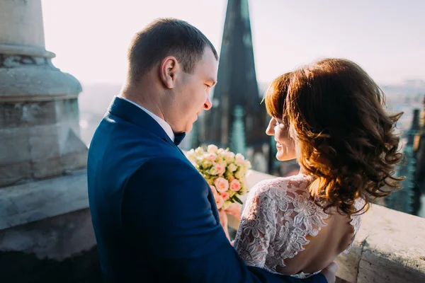 Gentili bellissimi sposi che si tengono per mano con bouquet che si guardano l'un l'altro sull'antico balcone, primo piano — Foto Stock