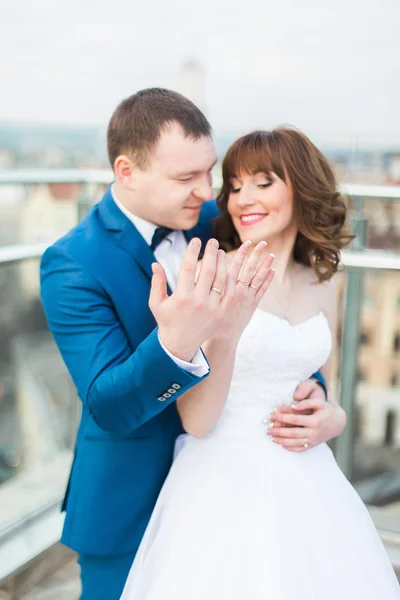 Счастливая улыбающаяся свадебная пара на террасе, показывающая свои кольца — стоковое фото