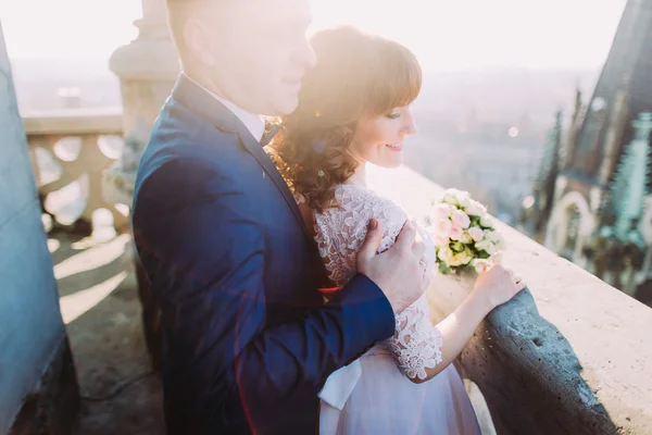 Bello sposo abbracciare sposa sensuale da dietro sul vecchio balcone con grande paesaggio urbano backgraund, primo piano — Foto Stock
