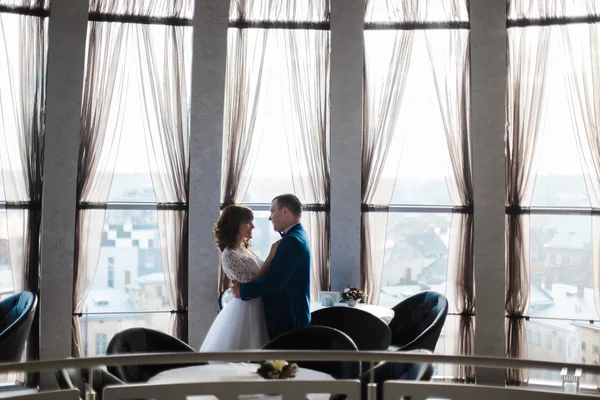 Bela noiva e noivo em restaurante vazio abraçando pelas janelas — Fotografia de Stock