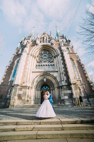 Noiva linda feliz e elegante noivo bonito no fundo de uma igreja de construção incrível na cidade — Fotografia de Stock