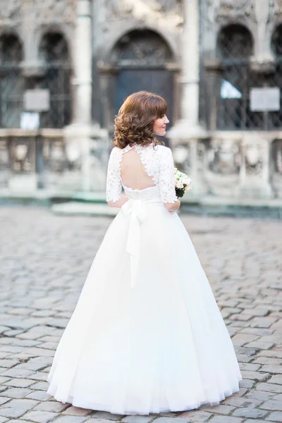 Giovane sposa sorridente posa di nuovo con bouquet di rose, paesaggio urbano sullo sfondo — Foto Stock