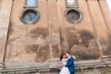 Muhteşem gelin gelin elbise ve yakışıklı damat eski kilise kahverengi duvara yakın sarılma