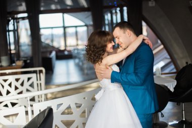 Restoranın modern iç mekanlarında yüz yüze kucaklayan yakın çekim mutlu gelin ve damat