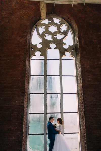Casal feliz abraçando braços na frente da velha janela gótica — Fotografia de Stock