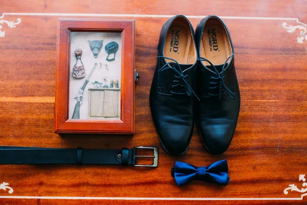 Close up de acessórios do homem moderno. Bowtie azul, sapatos de couro preto, cinto e lembrança em fundo rústico de madeira — Fotografia de Stock