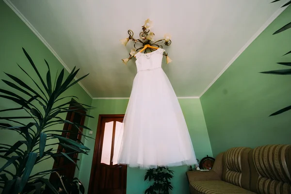 Vestido de novia blanco ilegal colgando de lustre en la habitación del hotel —  Fotos de Stock