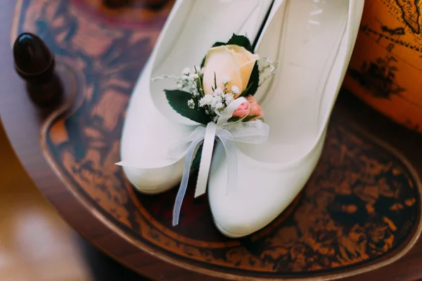 Крупный план элегантных свадебных туфель с милым маленьким бутоньером на винтажном фоне — стоковое фото