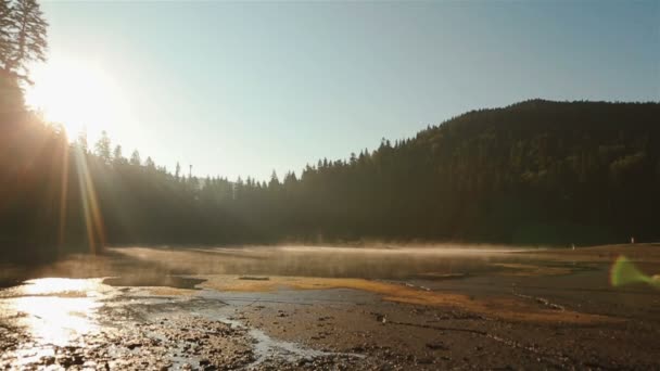 Ikuinen harmonia ihmisen ja luonnon välillä. Kaunis viehättävä Synevir järvi ihana auringonlasku. Henkeäsalpaava Karpaattien vuoret ja pari rakastunut kävely rannalla taustalla — kuvapankkivideo