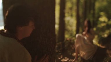 Young carpathian countryman spying on beautiful forest nymph while she combing her braids. Magic world of Carpathian mountains