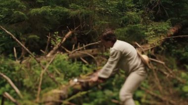 Geleneksel Ukraynalı giysiler içinde genç oduncu Karpat dağlarının yeşil ormanında odun kesiyor.
