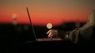 Kadının elinde kırmızı manikür sunset bulvarında dizüstü bilgisayarlar klavyede yazarak ile kapatın. Genç kadın eski Avrupa şehri bulanık arka plan üzerinde Facebook sohbet