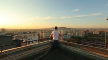 Genç yakışıklı şık işadamı endüstriyel cityscape arka planda gökdelenin çatı üzerinde