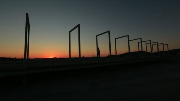 Silhueta de mulher pensativa solitária andando sozinha na ponte de alta tecnologia no pôr-do-sol vermelho — Vídeo de Stock