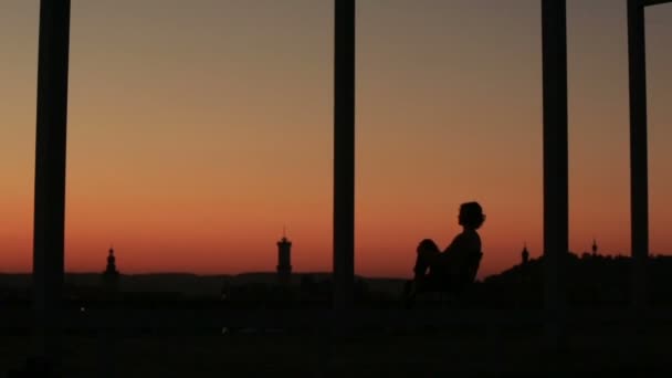 Silhouette eines schönen Mädchens beim Meditieren im Sonnenuntergang vor dem Hintergrund der Stadt — Stockvideo