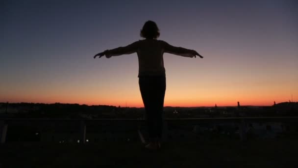 Silhuett av ung kvinna att höja händerna till solen vid solnedgången på bakifrån. Ögonblick av frihet och glädje — Stockvideo