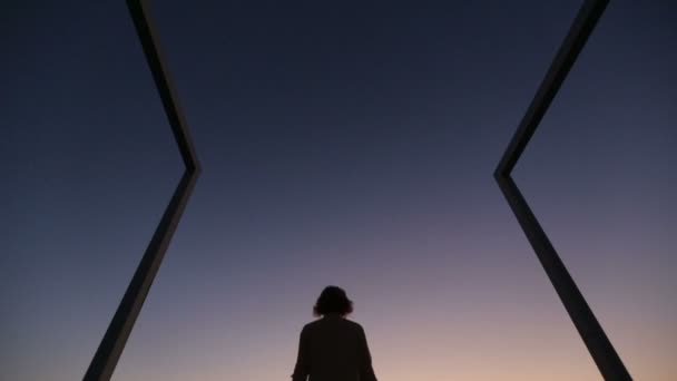 Silueta de mujer joven levantando las manos al cielo en el crepúsculo. Puente moderno de alta tecnología sobre fondo — Vídeos de Stock