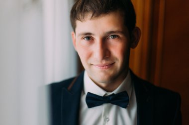 Esmer yakışıklı mavi yay pencere poz bağla, sabah hazırlanıyor damat