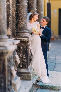 Güzel gelin buket eski bina sütunlar arasında ile arkadan sarılma duygusal romantik damat