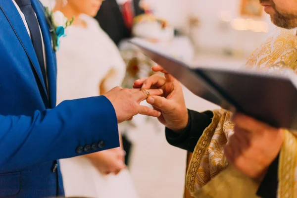 The priest putting a ring on grooms finger during traditional wedding in church — Stock Photo, Image