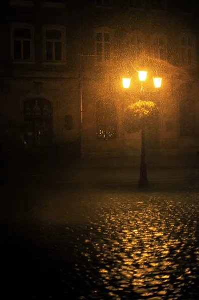 Nebbia autunnale in città. Lanterna solitario brilla sulla strada notte piovosa — Foto Stock