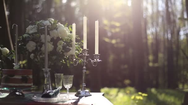 Primer plano de candelabro vintage blanco en la mesa decorada de boda en el bosque. Ramo de rosas blancas sobre fondo. Cena romántica en el bosque — Vídeo de stock