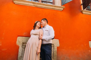 Şehvetli kaç sarılma ve birbirlerine turuncu duvarın önünde dokunmadan