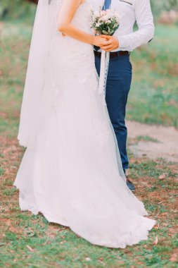 Gelin ve damat gelin buketi beyaz çiçek tutan açık havada, kapatmak