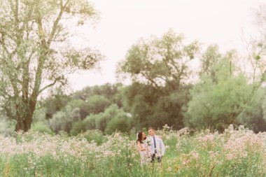 Yaz çayır kır çiçekleri ile onun yakışıklı damat arkasından kucaklayan güzel gelin