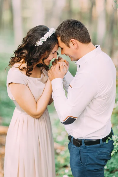Красивый мужчина и улыбающаяся женщина обнимают лбы, обмениваясь нежностью в весеннем парке — стоковое фото