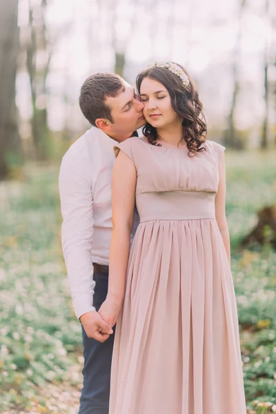 Un par de amantes en la cita en el parque, joven abrazándose tiernamente por detrás de su feliz novia sonriente, besándose la mejilla con los ojos cerrados — Foto de Stock