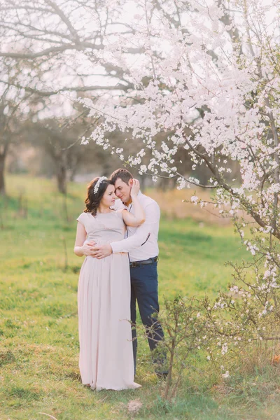 Liefde en tederheid. Mooie jonge liefdevolle paar omarmen in bloei in het voorjaar tuin. Romantisch daten — Stockfoto