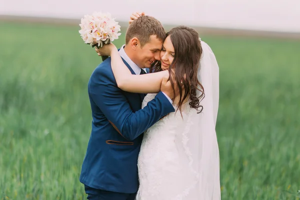 Hermosa pareja de boda, novia, novio abrazando en el campo de hierba verde alto, primer plano —  Fotos de Stock