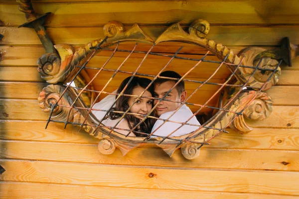 Pareja feliz mirando por la ventana de madera — Foto de Stock