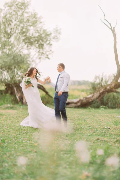 Feliz novia con estilo elegante novio bailando en el fondo de hermosos árboles en el parque — Foto de Stock