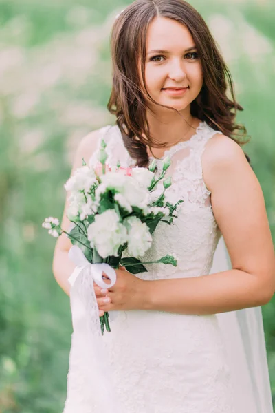 Portrait of beautiful smile bride holding bouquet while standing in park, close-up — Stok Foto