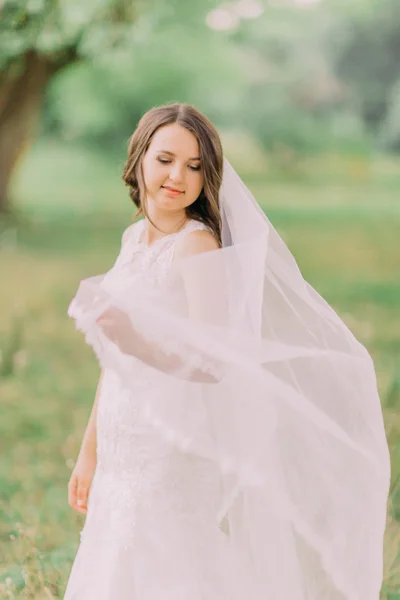 Vackra bruden i vit klänning spelar med slöja, våren grön park på bakgrund — Stockfoto