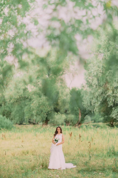 Luxo elegante jovem noiva no fundo da primavera ensolarado floresta verde — Fotografia de Stock