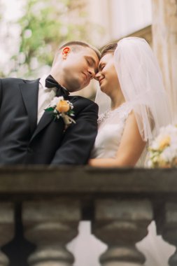 Güzel gelin ve damat alınlarına antik çit balkon kapalı gözler ile dokunmadan nazik yakın çekim