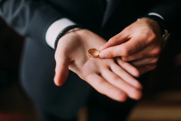 Anéis de casamento de ouro na palma dos noivos — Fotografia de Stock