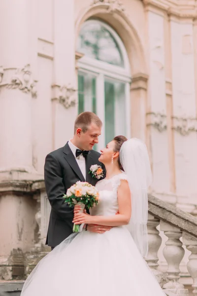 Vackra gift par leende och kramas nära gammal byggnad vägg närbild — Stockfoto