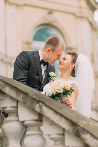Χαριτωμένο παντρεμένο ζευγάρι, αγγίζοντας μύτες κοντινό στέκονται σε αντίκα μπαλκόνι με στήλες — Φωτογραφία Αρχείου