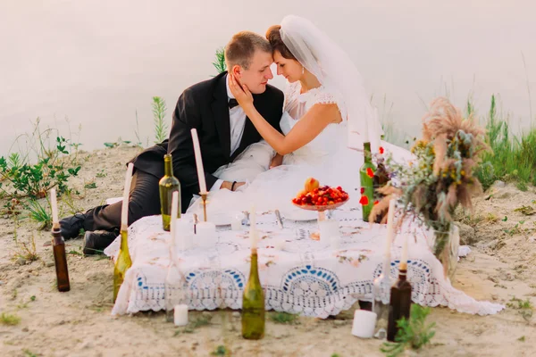 Casal jovem abraçando à noite romântica com velas na praia de areia — Fotografia de Stock