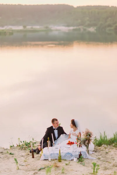 Junges Hochzeitspaar verbringt einen romantischen Abend mit Kerzen am Sandstrand — Stockfoto