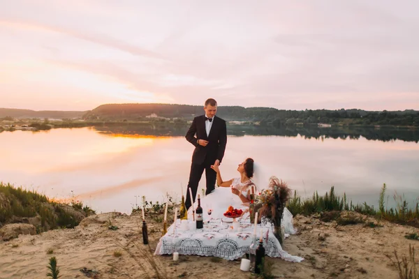 Bella sposa dà mano uomo elegante alla serata romantica con candele sulla spiaggia di sabbia — Foto Stock