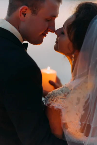 Happy bride and groom at moment before kiss holding a candle, close-up — Stock Photo, Image