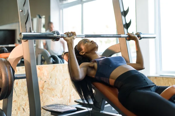 Sexy hermosa mujer afroamericana entrenando con barra de pesas en el gimnasio — Foto de Stock
