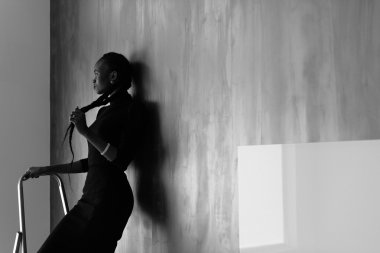 Koyu stüdyo arka plan, siyah-beyaz onu kalın plait dokunmadan uzağa bakan güzel afrikalı ya da siyah amerikalı kadın Yan görünümü