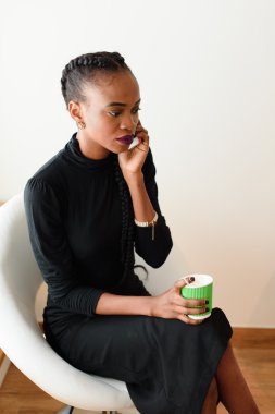 Tek kullanımlık bardak tutarken ofiste mobil iş kadını cep telefonuyla konuşuyor