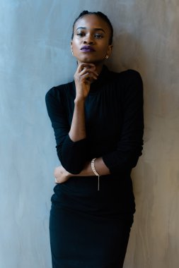 Zarif Afrika veya siyah Amerikalı kadın gri arka plan üzerinde çene altında el ile bakıyor